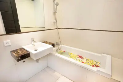 a white bathroom with a sink and a mirror at InKuta Residence and Villa in Seminyak