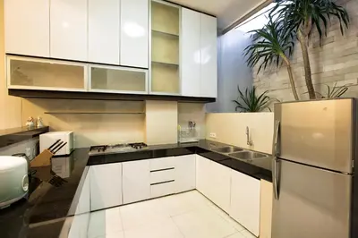 a kitchen with white cabinets and a refrigerator at InKuta Residence and Villa in Seminyak