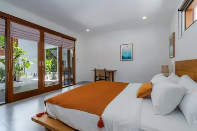 a bedroom with a large bed and a balcony at Beta Stay and Surf in Canggu