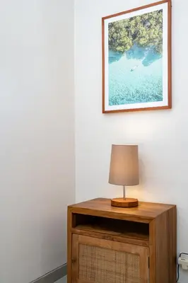a lamp on a wooden table with a picture on the wall at Beta Stay and Surf in Canggu