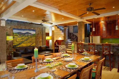 a dining room with a large wooden table with chairs at Villa SanSam Seminyak in Seminyak