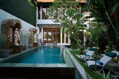 a swimming pool in a garden with chairs and a house at Villa SanSam Seminyak in Seminyak