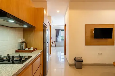 a kitchen with a stove and a tv on the wall at Adikara Apartment by Betterplace in Canggu