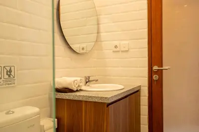 a bathroom with a sink and a mirror and a toilet at Adikara Apartment by Betterplace in Canggu