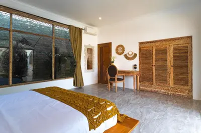 a bedroom with a bed and a desk and a window at Villa Nirvana Seminyak in Seminyak