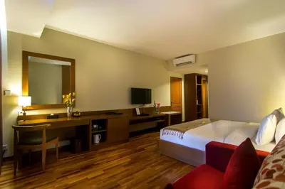a hotel room with a bed and a desk and a mirror at Seminyak Square Hotel And Villas in Seminyak
