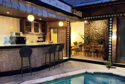 a kitchen and an outdoor bar with chairs and a pool at Villa Mutti in Seminyak
