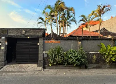 a building with a garage with plants and palm trees at Villa Mutti in Seminyak
