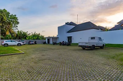 a white building with cars parked in a parking lot at Villa Yolanda - Seminyak Beach in Seminyak