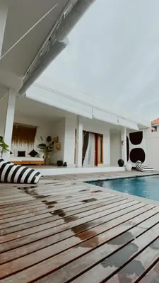 a swimming pool with a wooden floor and a building at Villa Hope Bali in Kerobokan