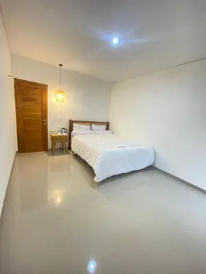 a white bedroom with a bed and a table at Home Stay Room In Bali Near Sanur Beach in Sanur
