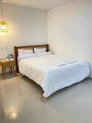 a bedroom with a large white bed and a table at Home Stay Room In Bali Near Sanur Beach in Sanur