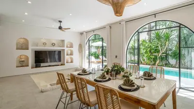 a dining room with a table and chairs and a pool at Villa Unna in Canggu by Elite Havens in Canggu