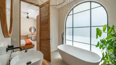 a bathroom with a large white tub and a bedroom at Villa Unna in Canggu by Elite Havens in Canggu