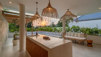a kitchen and living room with a couch and chandeliers at Villa Unna in Canggu by Elite Havens in Canggu