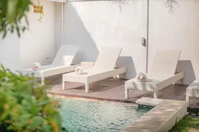 three chairs and a swimming pool next to a house at Villa Toto Seminyak in Seminyak