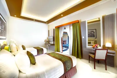 a hotel room with two beds and a desk at The Banyumas Suite Villa Legian in Legian