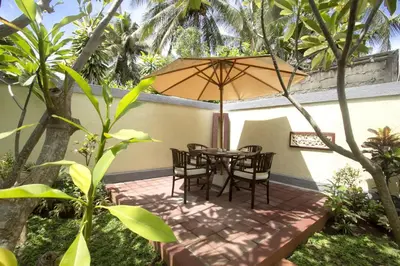 a patio with a table and chairs under an umbrella at Frangipani Homestay in Nusa Dua