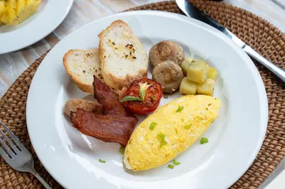 a white plate with breakfast food on a table at The Kifaraju Nusa Dua Bali in Nusa Dua