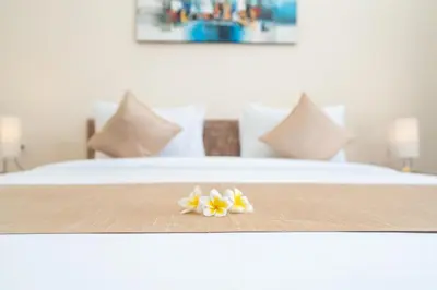 a close up of a bed with two flowers on it at The Kifaraju Nusa Dua Bali in Nusa Dua