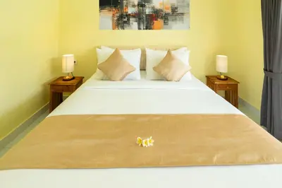 a bedroom with a large white bed with two lamps at The Kifaraju Nusa Dua Bali in Nusa Dua