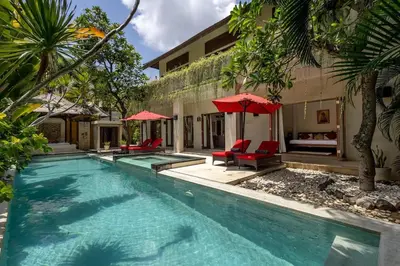 a swimming pool with chairs and umbrellas next to a house at Luxury 3-Bedroom Villa With Private Pool Seminyak Village in Seminyak