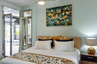 a bedroom with a large bed with a painting on the wall at Villa Nari - GG100X Seminyak, Bali in Seminyak