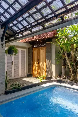 a pergola over a swimming pool in front of a house at Villa Nari - GG100X Seminyak, Bali in Seminyak