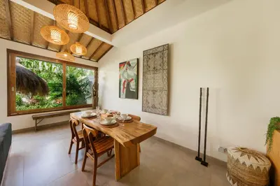a dining room with a wooden table and chairs at Villa Kepompong Seminyak - 1BR Private Pool Villa in Seminyak