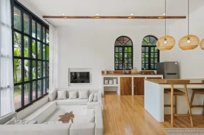 a living room with white furniture and large windows at Mediterranean 2BR Villa Ellure Ember with Pool & Lush Garden in Jimbaran