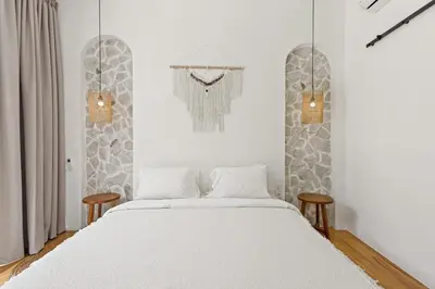 a white bedroom with a bed and two chairs at Mediterranean 2BR Villa Ellure Ember with Pool & Lush Garden in Jimbaran