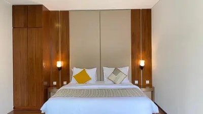 a bedroom with a bed with two yellow pillows at YY Villa Seminyak - 4BR Luxury Private Villa in Seminyak