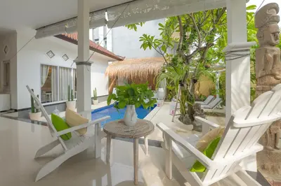 a porch with white chairs and a table and a tree at Smile - One Bedroom Villa in the Seminyak center in Seminyak