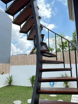 a wooden spiral staircase in a backyard with a fence at Wakajima House Kuta Utara in Kerobokan