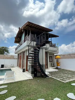 a house with a spiral staircase next to a pool at Wakajima House Kuta Utara in Kerobokan