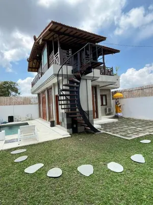 a house with a spiral staircase in the yard at Wakajima House Kuta Utara in Kerobokan