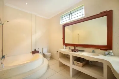 a bathroom with a tub and a sink and a mirror at Legian Blue Ocean Villa in Seminyak