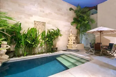 a swimming pool with plants and an umbrella at Legian Blue Ocean Villa in Seminyak