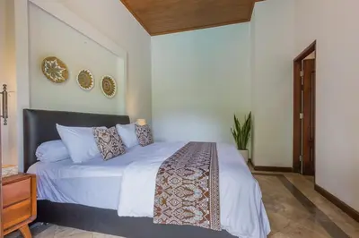 a bedroom with a bed with white sheets and pillows at Castila Saraswati - Tranquil 4BR Villa in Kayu Aya in Seminyak