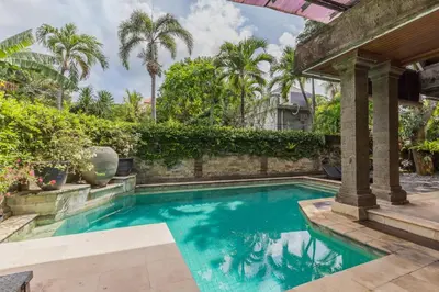 a swimming pool in a backyard with palm trees at Castila Saraswati - Tranquil 4BR Villa in Kayu Aya in Seminyak