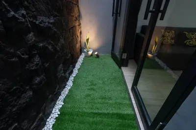 a room with a wall with green grass and a stone wall at Mezzanine Luxury Smart Room - Sanur in Sanur