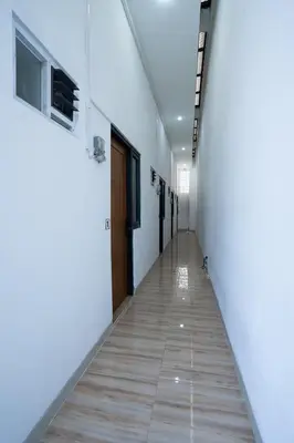 a corridor of an office with white walls and wooden doors at Mezzanine Luxury Smart Room - Sanur in Sanur