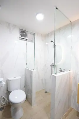 a white bathroom with a toilet and a shower at Mezzanine Luxury Smart Room - Sanur in Sanur