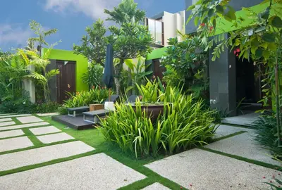 a garden in front of a building with plants at Cicada Luxury Townhouses in Seminyak
