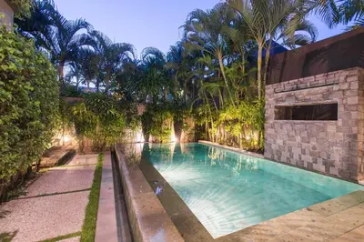 a swimming pool in a yard with palm trees at Cicada Luxury Townhouses in Seminyak