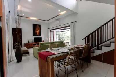 a dining room and living room with a table and chairs at Bali mansion kuta in Legian