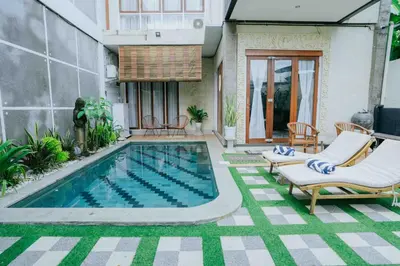 a swimming pool in a yard with chairs and a house at Shantia Villa 10 minutes walk to Double Six Beach Seminyak in Seminyak