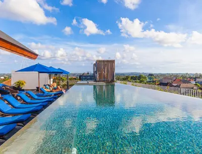 a large swimming pool with blue lounge chairs on a building at Watermark Hotel & Spa Bali in Jimbaran
