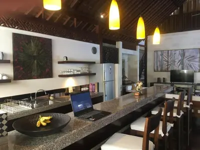 a kitchen with a bar with a laptop on a counter at Villa Jepun Seminyak in Canggu