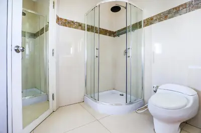 a bathroom with a toilet and a glass shower at Canggu Art Loft - Luxury Stay with Berawa View 2BDR in Canggu